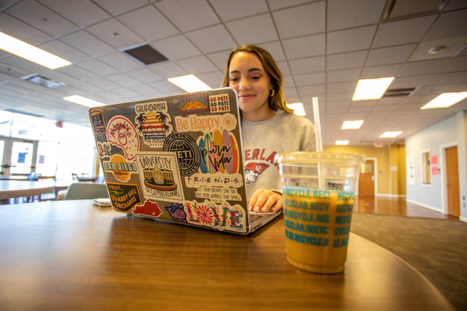 Young woman using laptop that's covered in stickers