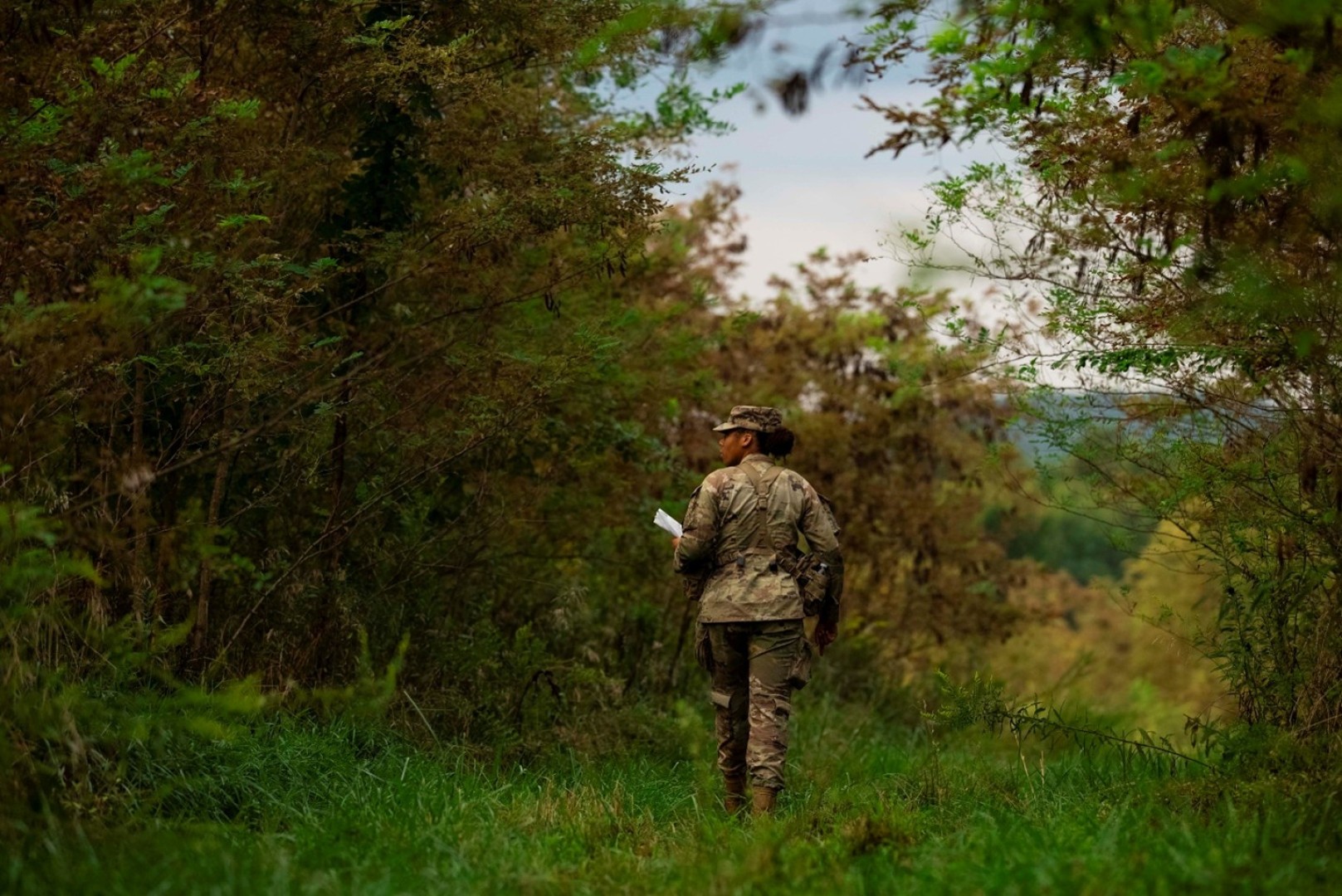 A female RTOC student navigates a wooded area during training. 