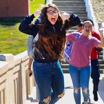 A student jumping for a picture while on a boardwalk