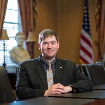 A young adult seated at a conference table