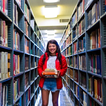 Student standing next to bookshelves