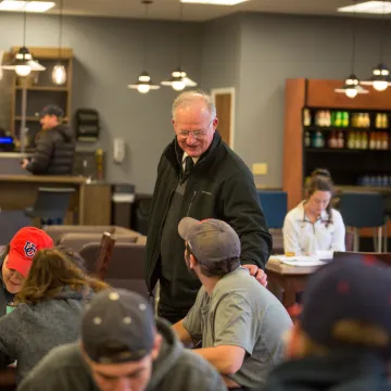 An older man speaking to a young adult