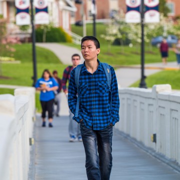A student walking across a bridge