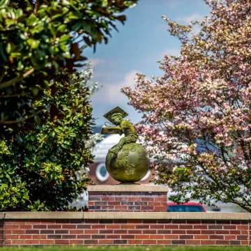 Bronze statue of a boy studying while seated on a globe