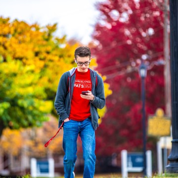 A student looking at their phone while walking