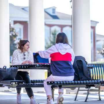 Two students seated at a table ouside