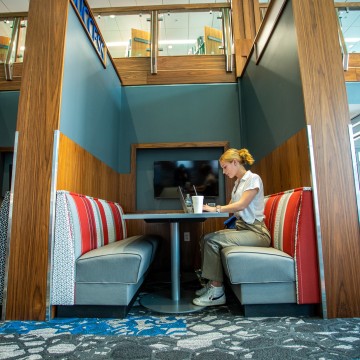 A student sitting in a booth and using a laptop
