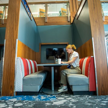 A student sitting in a booth and using a laptop