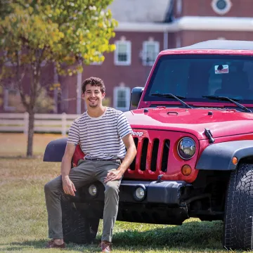 A student poses with his vehicle on campus. 