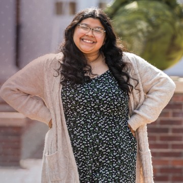A student poses after class in front of the education building. 
