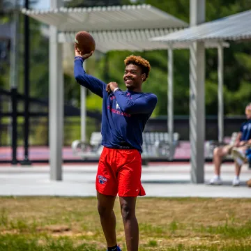 A student throws a football in Patriot Park.