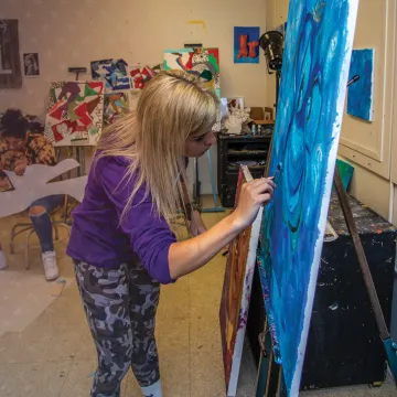 A female art student paints on her canvas. 