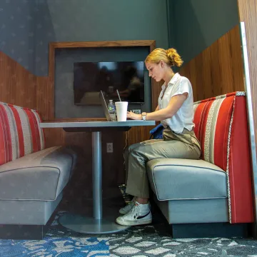 A female college student studies alone at a booth in the library.
