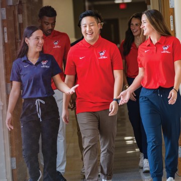 Six physical therapy students walk down a hallway after class. 