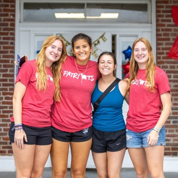 Four female students pose together in front of their dorm on move in day. 