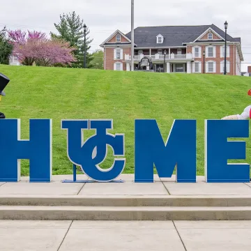 The Mr. Peanut mascot and Cumberlands mascot Patriot Pete stand by the home sign on campus. 