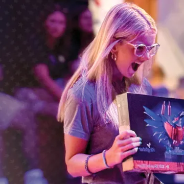 A female holds a Lego set she won during a college orientation event. 