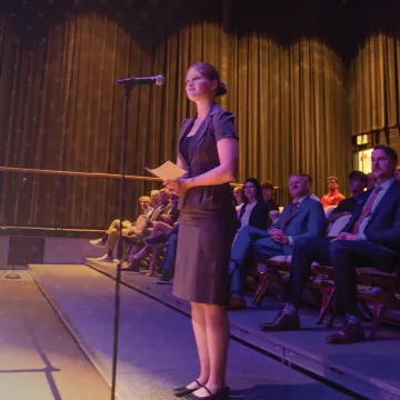 A female law student stands at a microphone and asks a question of Supreme Court members during a campus event. 