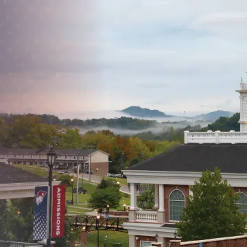 Fog rises above the university campus center during an early fall morning. 
