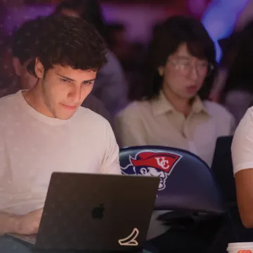 A group of students shown sitting in a seminar with their laptops out. 