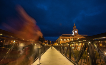 A student walks across the viaduct at night. 