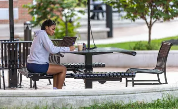 A student sits outside in the quad doing coursework 