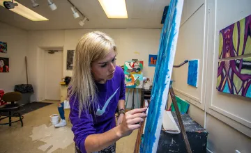 An art student works on a painting in the studio. 