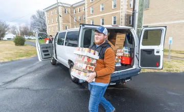 A student carries donated food into a food pantry. 
