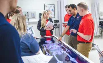 Physical therapy students participate in an anatomy exercise with their professor. 