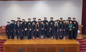 The first graduating class from the DPT program post on stage for a photo. 