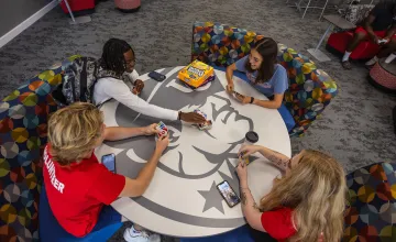 Students play cards around a table in the student center.