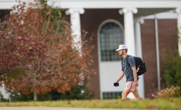A student walks to class with his backpack. 