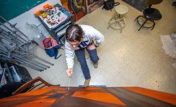 A male art student works on an abstract canvas. 