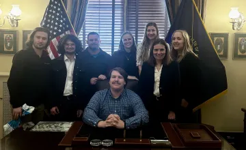 Students from the Upsilon Upsilon honor society at Cumberlands pose behind a desk. 