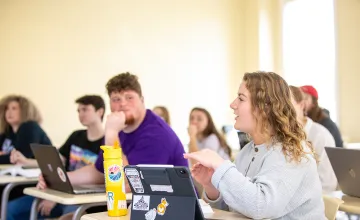 A female student discusses a topic in class. 