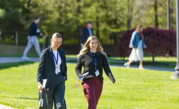 Two female business students walk across campus during the annual business forum. 