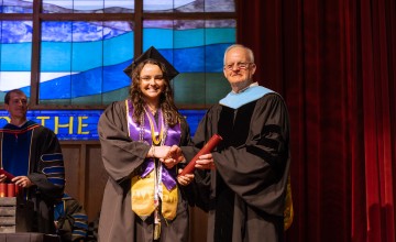 A female honors student accepts her diploma from President Cockrum. 