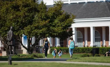 Two students walk on campus near the Lincoln statue. 