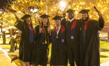 Five students pose in their caps and gowns while holding their diplomas following Cumberlands December graduation ceremony. 