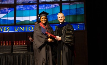 A female graduate accepts her diploma from President Young. 