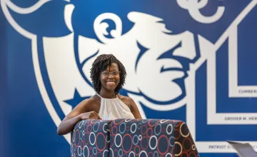 A female student sits in a chair in front of a wall with the Cumberlands logo in the student success center. 