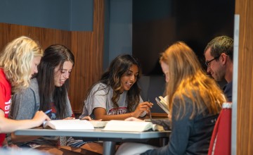 A group of students study together at a table in the library. 