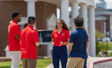 A female physical therapy student leads a discussion among a group of students. 
