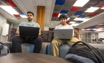 Two male executive students use their computers while in the student success center. 