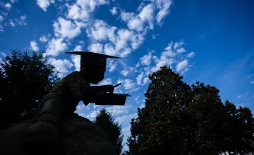 A statue on campus is shaded in the foreground with a dramatic blue sky behind it. 