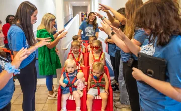 Workers at the Mighty Oaks Early Learning Center push children in a stroller. 