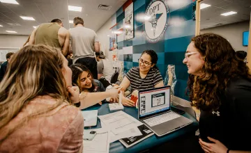 Four female physical therapy students work through a project in the PT lab. 