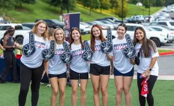 Six female students hold up Pats foam fingers during a welcome week event. 