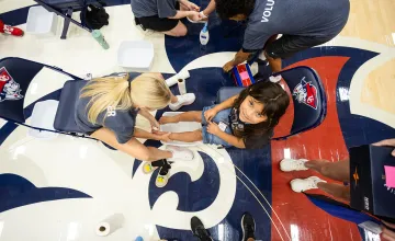A college volunteer washes the feet of a local student prior to giving her a new pair of shoes during the annual Shoes 4 the Soul event. 