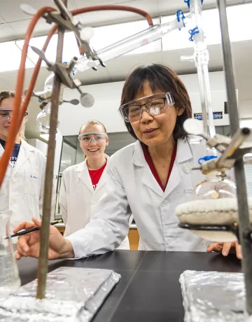 A chemistry professor shows an experiment to students in a lab.